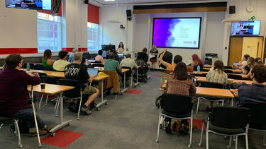 People sat a desks in front of a projector screen 