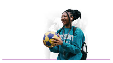 A young female student, smiling holding a football