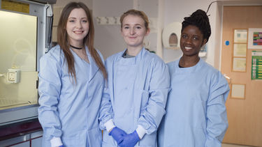 Students in the lab wearing blue lab coats and gloves