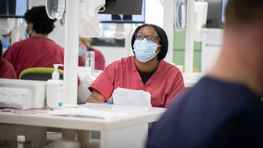 Dental students in red scrubs and masks