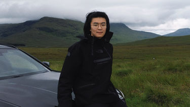 Kaiteng Zhang stood next to a car in the countryside