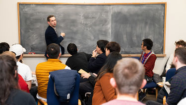 Teacher at blackboard in front of maths students