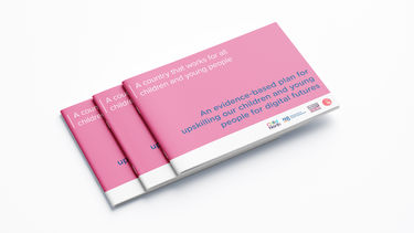 An image of a stack of the report brochures on a plain surface, the report cover is pink.