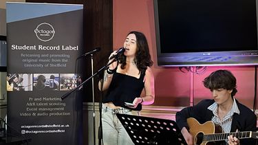 A student musician performing at an open-mic night in a pub at the University of Sheffield