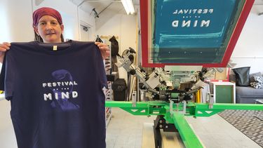 A staff member holding a Festival of the Mind T-Shirt