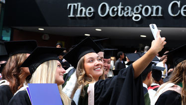 Happy students taking a selfie outside at graduation