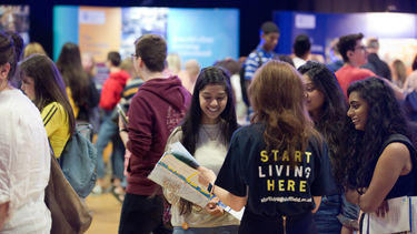 A group of students in the Octagon smiling and looking at a map