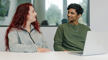 Two students in conversation in a seminar room