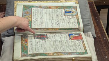 Medieval book lying open on the table with visibly colourful text