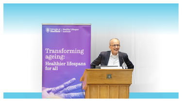 A speaker at a conference dais with a banner that reads Transforming Ageing - Healthier lifespans for all