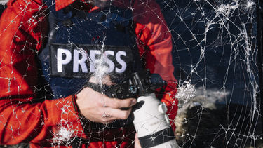 A press photographer in front of smashed glass