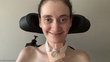 Gemma in her mobility aid with a tracheostomy tube in her neck