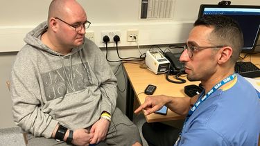 A doctor talks to a patient with equipment attached to his wrist