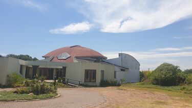 A large building with a domed roof on a dirt road