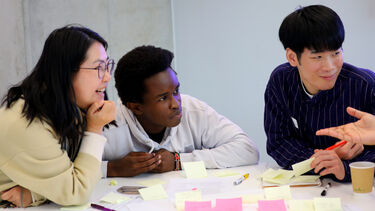 Group of 3 students around a table working on ideas