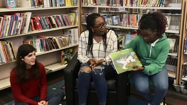 A young girl reading a book in the children's section of a library
