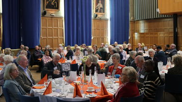 Heritage Circle lunch attendees sitting at large round tables in a wood-pannelled room