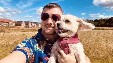 Man in Hawaiian shirt and sunglasses with a dog 