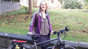 Sarah smiling with her bicycle