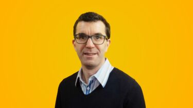 Headshot of Mike Brewer on a yellow background