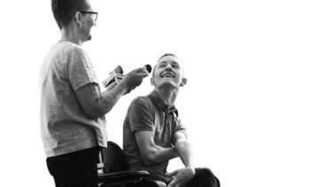 A person in a wheelchair and a standing person