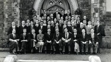 A group of 30-40 scholars in black and white, seated outside in a formal photograph