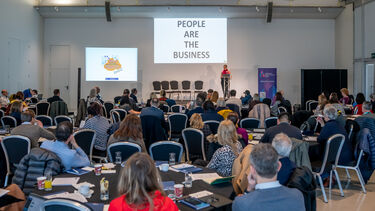 A room full of people listening to a presentation.
