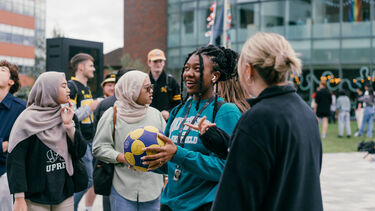 Group of people chatting, one holding a netball.