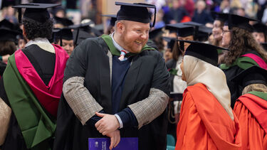 Two graduates looking at each other happily