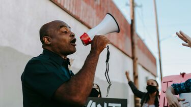 A man speaking through a megaphone to a crowd of protesters