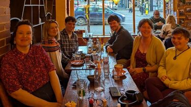 A group of people sat around a table in a cafe, with paper lanterns hanging above them