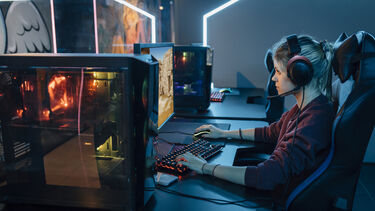 A woman wearing a headset playing a video game on a PC