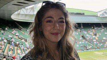 A woman with blonde hair with a tennis court in the background