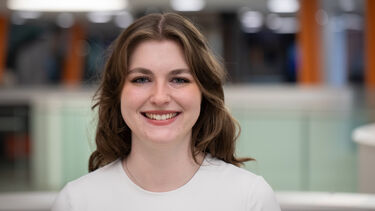 Headshot of a person with long wavy hair smiling towards the camera
