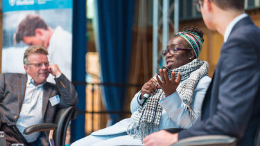  Rosamund Adoo-Kissi-Debrah, Director of the Ella Roberta Foundation, speaking at the Sustainability Symposium 2024 next to Tom Hunt, Leader of Sheffield City Council and Tony Ryan, Co-Director of the Grantham Centre for Sustainable Futures
