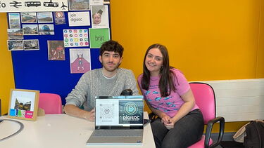 Two students sat at an exhibition table