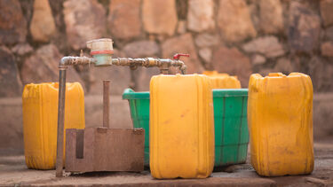 Jerrycans and buckets next to a tap to collect water 