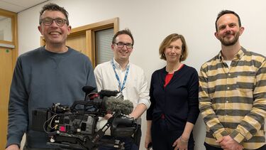 BBC Cameraman Jon Hillyer, Professor Andy Swift, Alison Holt and Director and Producer Jospeh McAuley pose smiling for a group photo with a television camera in the foreground