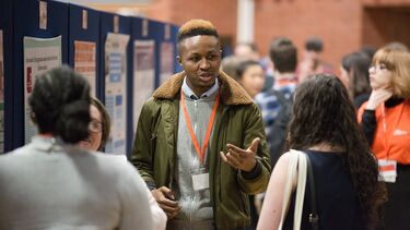 Photograph from the SURE Showcase of a student presenting their research poster to other students