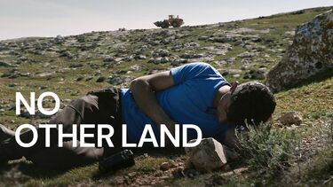 A child lying on a hill with the text 'No Other Land' overlaid