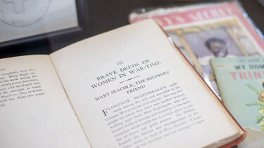 A display cabinet with an open book, on a chapter titled: 'Brave deeds of women in war-time'