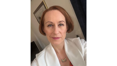 A woman in a white blazer, with short red hair