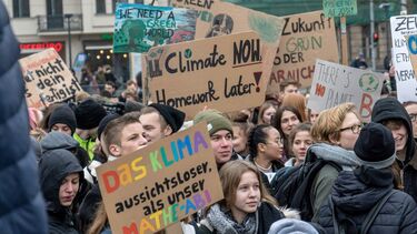 A crowd at a climate protest holding up banners