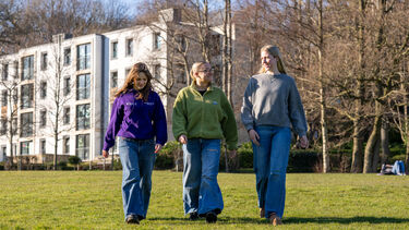 Mentor and students walk across the Paddock in front of Lawrencefield