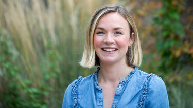 Blonde woman wearing a denim shirt smiling at the camera