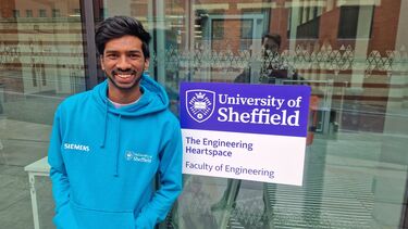 Smiling student wearing a blue hoody standing in front of the Heartspace