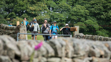 A group of smiling Big Walk 2025 participants approaching a field gate