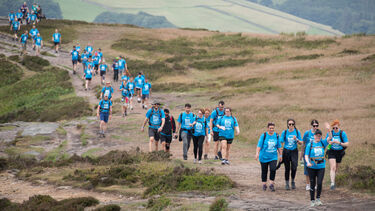 A large group of Big Walk participants making their way along the crest of a hill in blue Big Walk 2025 tshirts
