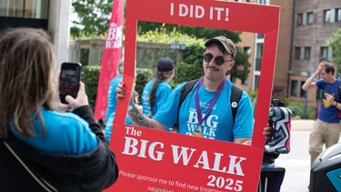 Vin Silvestri pictured at the Big Walk finish line at The Edge, holding a giant photo frame that reads 'I did it! The Big Walk 2025'