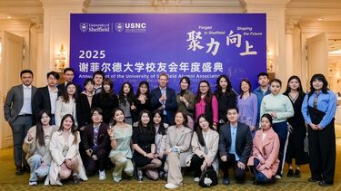 A group of international alumni posing in front of a University of Sheffield display at an event in Beijing